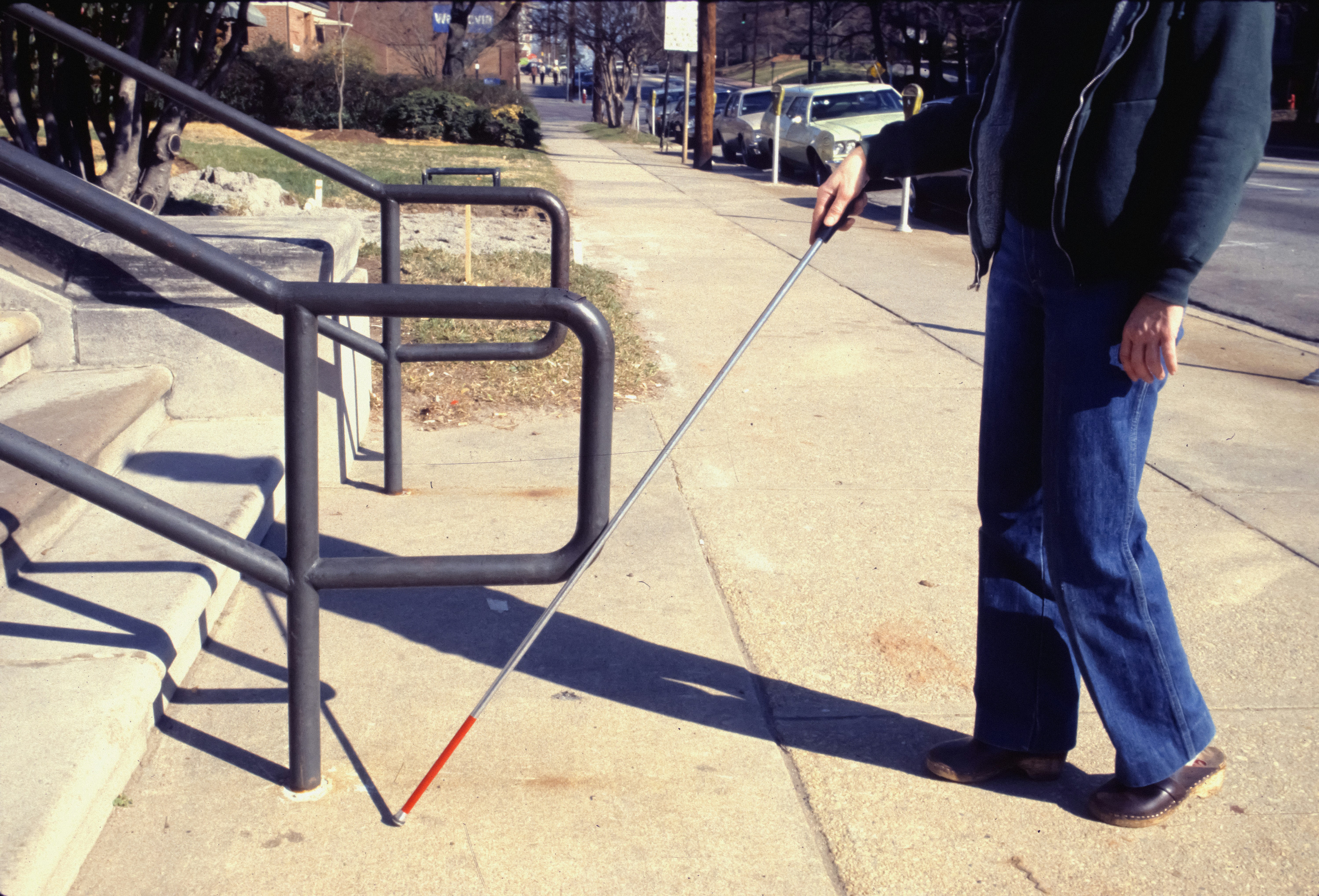 Blind man using a walking stick around stairs